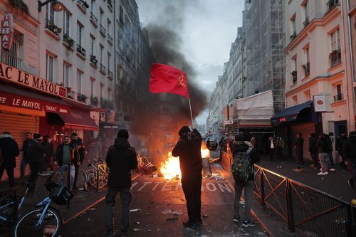 Members of Kurdish community waves the Kurdish communist flags next to a barricade on fire at the crime scene where a shooting took place in Paris, Friday, Dec. 23, 2022. Skirmishes erupted in the neighbourhood a few hours after the shooting, as members of the Kurdish community shouted slogans against the Turkish government, and police fired tear gas to disperse an increasingly agitated crowd. A shooting targeting a Kurdish cultural center in Paris Friday left three people dead and three other