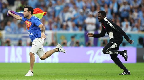 Security gives chase as a spectator holding a rainbow flag invades the field during Portugal's match with Uruguay.