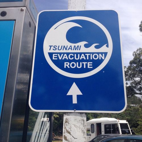 Un panneau d'avertissement de tsunami indique une voie d'évacuation à Cathedral Cove en Nouvelle-Zélande.