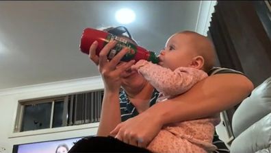 Baby being fed milk from a tomato sauce bottle.