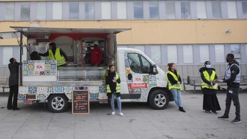 Volunteer distribute free lunch during an information campaign in several different languages about the coronavirus COVID-19 pandemic, in the Tensta suburb of Stockholm.