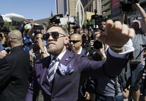 Conor McGregor waves to fans during the arrivals for their fight. (AAP)
