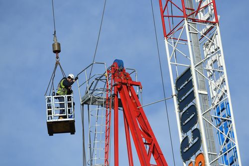 Two workers have been hoisted in the air to dismantle the damaged crane. Picture: AAP