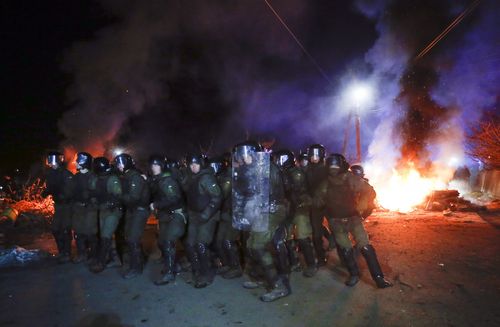 Ukrainian riot police prepare to push protesters, who planned to stop buses carrying passengers evacuated from the Chinese city of Wuhan, outside Novi Sarzhany, Ukraine.