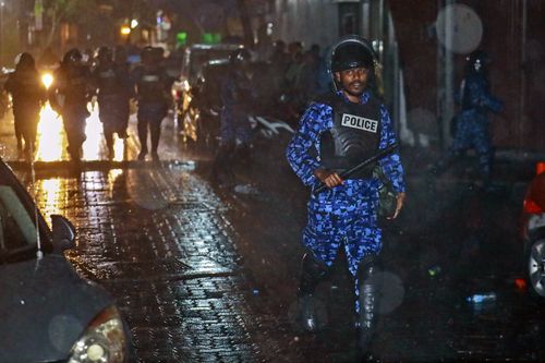 A Maldives policeman charges with baton towards protesters after the government declared a 15-day state of emergency. Picture: AAP