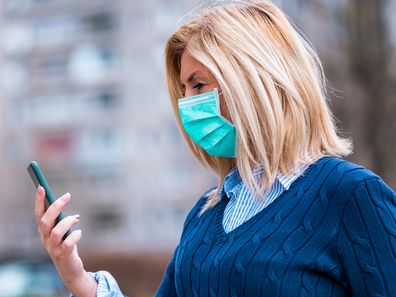 Woman wearing a face mask and using her phone.