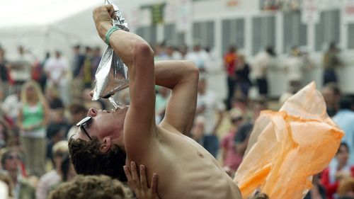 Festival-goer crowdsurfing and drinking cask wine at the same time. 