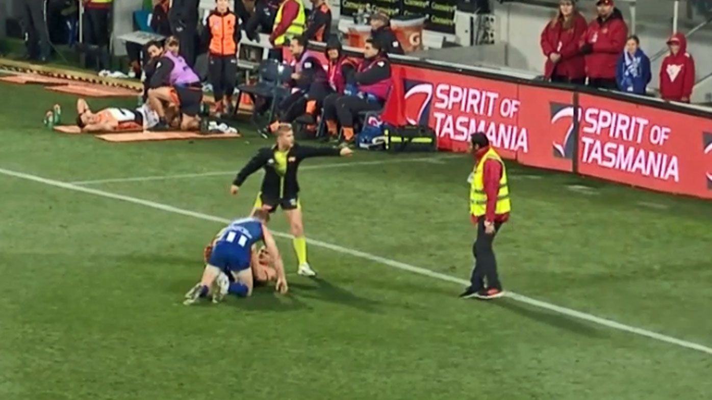 An AFL security guard steps onto the ground