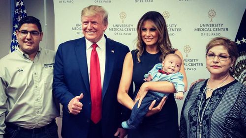 Donald Trump grins and gives a thumbs up while posing with a baby whose parents died in the El Paso massacre last Saturday.