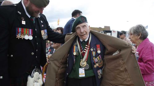 British D-Day veteran Harry Billinge opens his coat to show his medals.