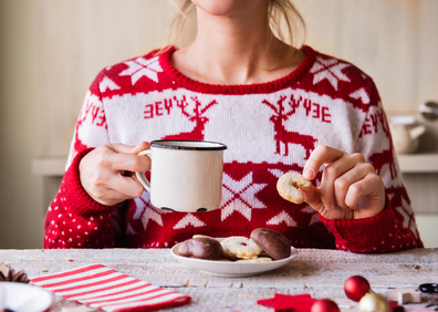 Woman in a christmas jumper eating cookies