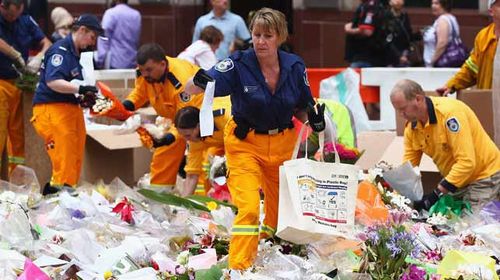 Volunteers pack up the floral tributes in Martin Place ahead of an expected rain shower. (Getty)