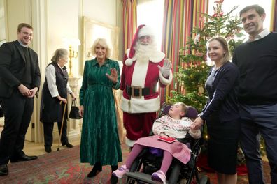 Queen Camilla poses with a man dressed as Father Christmas as she invited children, supported by Helen & Douglas House and Roald Dahl's Marvellous Children's Charity, decorate the Christmas tree and receive a few festive surprises at Clarence House on December 6, 2023 in London, England