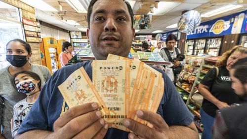 Hector Solis detiene i biglietti della lotteria acquistati con i suoi compagni della lotteria Powerball sabato in un negozio di liquori Bluebird a Hawthorne, in California.