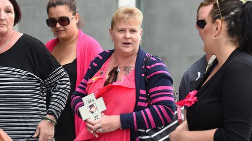 Marlene Locke holds a cross with a photo of her daughter as she arrives at the Supreme Court last year. (AAP)