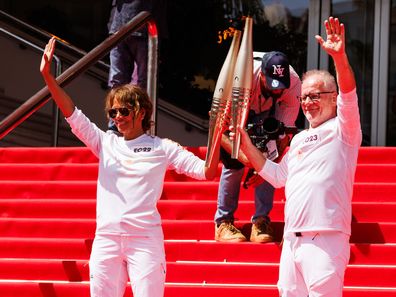 CANNES, FRANCE - JUNE 18: Actress Halle Berry (L) and Thierry Fremaux carrythe Olympic Torch in front of the Palais des Festivals during the Cannes Lions International Festival Of Creativity 2024 - Day Two on June 18, 2024 in Cannes, France. (Photo by Richard Bord/WireImage)