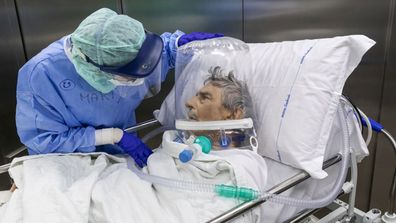 A nurse attends to a COVID-19 patient that is wearing a CPAP helmet while he is moved out of the Intensive Care Unit (ICU) of the Pope John XXIII Hospital on April 7, 2020 in Bergamo, Italy.