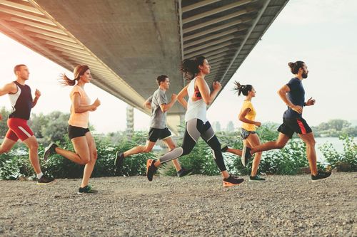 Group of joggers run under bridge.