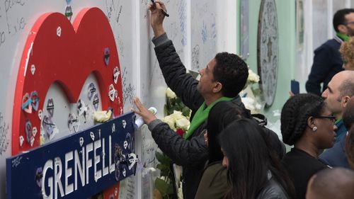 People gather  to sign a Grenfell tribute sign. Picture: Getty