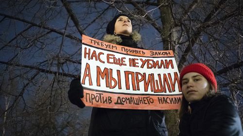 A woman holds a banner demanding Russia to change domestic violence laws. 