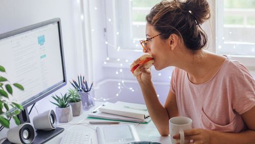 Woman eating while working from home.