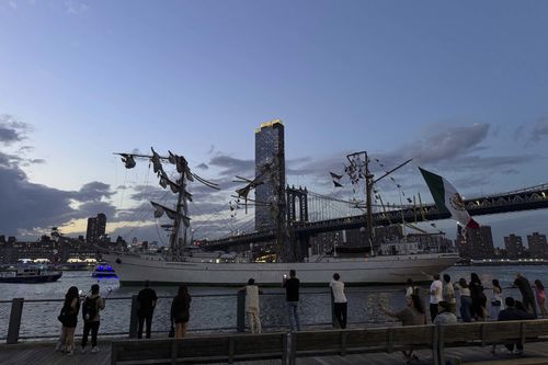 Pedestrians walking along Brooklyn Bridge Park look on as a masted Mexican Navy training ship sits stranded near the Manhattan Bridge after colliding with the Brooklyn Bridge.