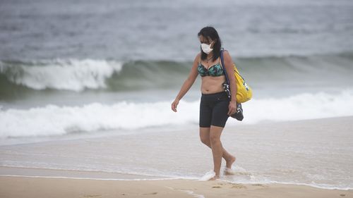 RIO DE JANEIRO, BRAZIL - MARCH 21: A beachgoer wearing a mask walks at Ipanema Beach during a lockdown aimed at stopping the spread of the (COVID-19) coronavirus pandemic.