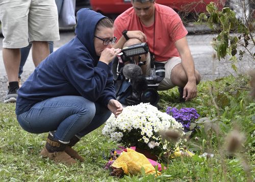 A woman kneels in mourning at the site where 20 people were killed when a limousine ran through a stop sign on its way to a birthday party.