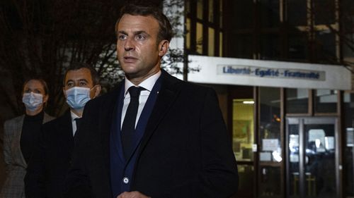 French President Emmanuel Macron, flanked by French Interior Minister Gerald Darmanin, second left, speaks in front of a high school Friday Oct.16, 2020 in Conflans Sainte-Honorine, northwest of Paris