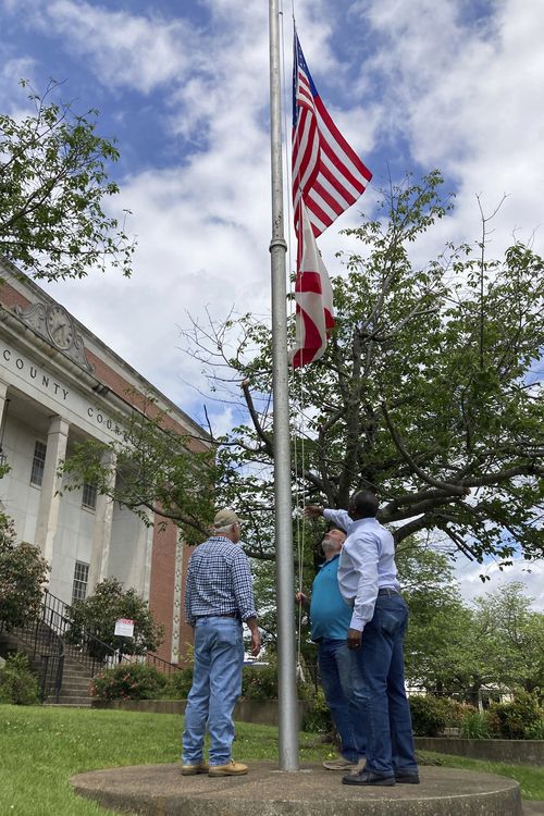 Men lower the U.S. and Alabama flag to half-staff at the Tallapoosa County Courthouse in Dadeville, Ala., on Sunday, April 16, 2023, hours after a fatal shooting less than a block away. 