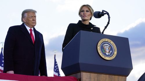 President Donald Trump listens as First Lady Melania Trump speaks before boarding Air Force One at Andrews Air Force Base, Md., Wednesday, Jan. 20, 2021.