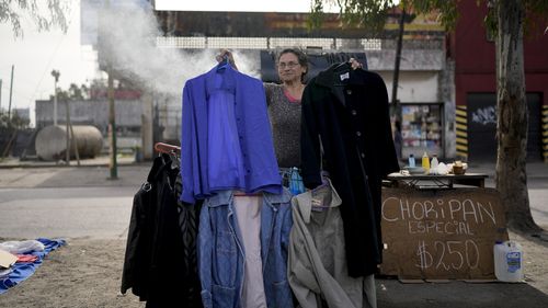 A vendor holds up secondhand garments.