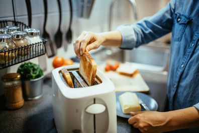 Woman using toaster to prepare breakfast at home