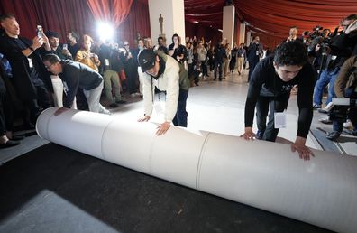 Crew members roll out the carpet outside the Dolby Theatre on Wednesday, March 8, 2023, in Los Angeles in preparation for Sunday's 95th Academy Awards. (AP Photo/Chris Pizzello)