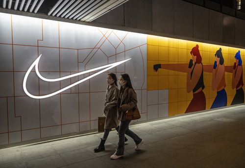 Women walk by a Nike store in Beijing, China.