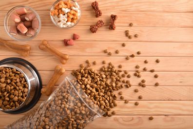 Background with various types of dry food for feeding the dog on wood table. Top view. Horizontal composition.