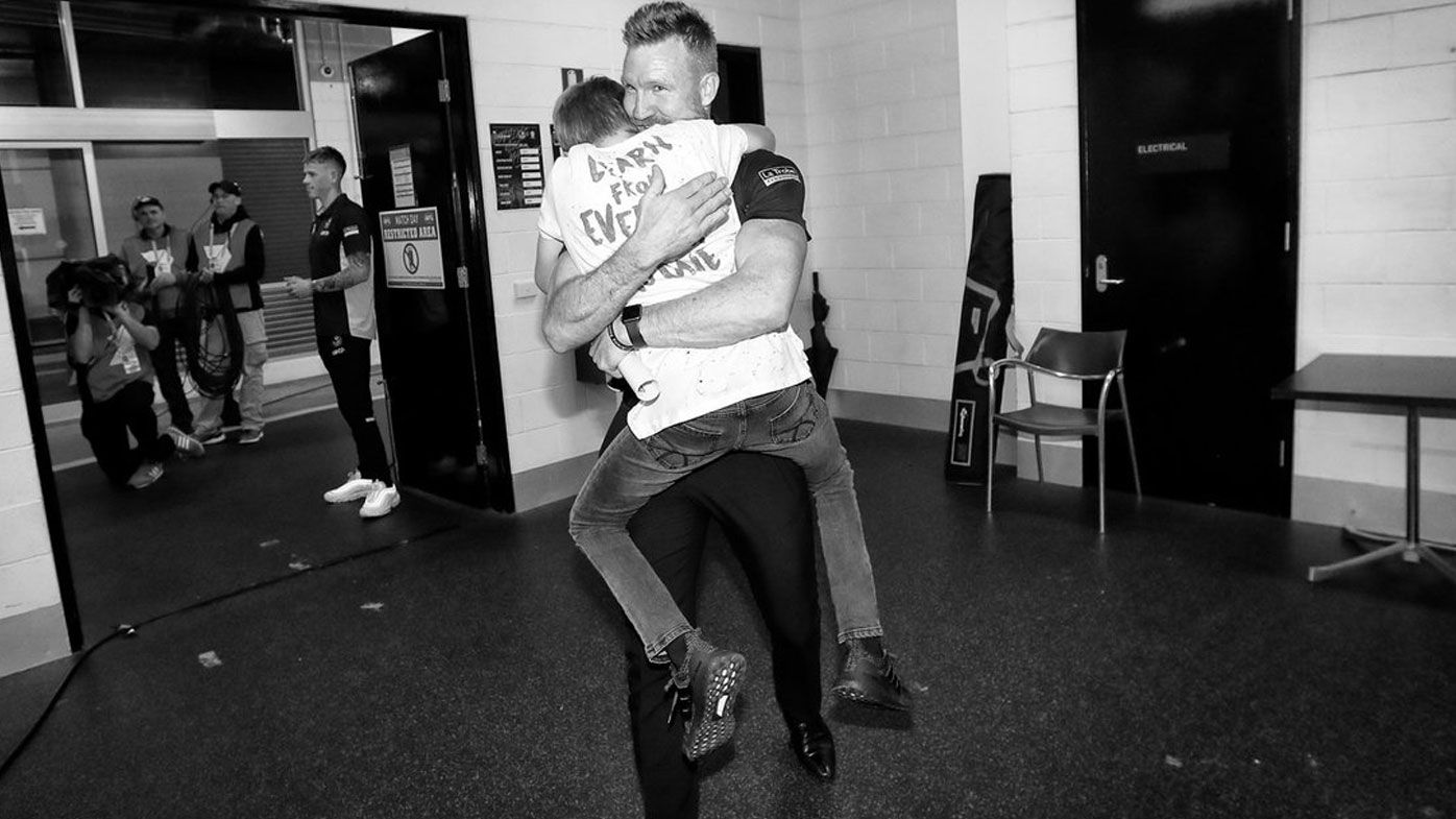 Collingwood coach Nathan Buckley embraces son after momentous AFL finals victory, tumultuous season