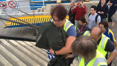 A wildlife volunteer brings the wallaby to shore wrapped in a blanket.