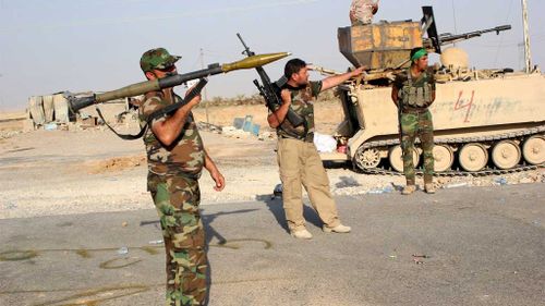 Members of the Iraqi Shiite militia, Kataib Hezbollah (Hezbollah Brigades), take up position during fighting against Islamic State. (AAP)