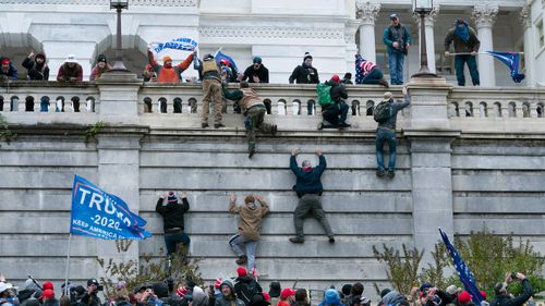 Rioting supporters of President Donald Trump climb the west wall of the the US Capitol in Washington.