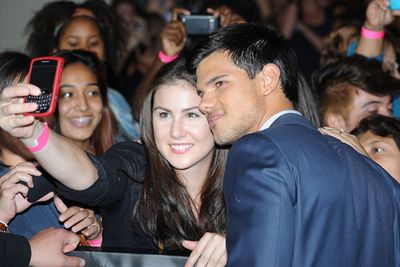 Taylor Lautner takes a photo with a fan as he arrives at the world premiere of "Abduction" in Hollywood.
