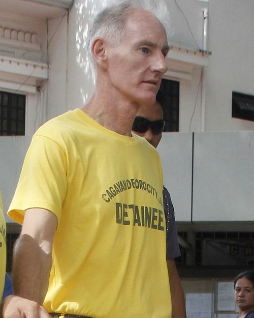 Australian Peter Gerald Scully in handcuffs as he arrives at Cagayan de Oro city hall in southern Philippines. Scully and his Filipino girlfriend Carme Ann Alvarez were charged with raping and trafficking two girls aged 9 and 12 in a southern Philippine city. Scully is also under investigation in the death of a girl whose remains were found inside his house in another southern province. (AAP)