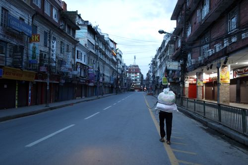 A Nepalese man carries sacks of wheat flour on his way back home during lockdown in Kathmandu, Nepal. Under the lockdown, flights and road travel have been halted, schools and businesses have been shut and people have been told to stay home. 