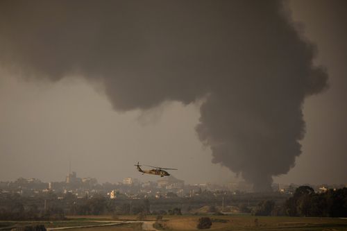 An Israeli helicopter flies a long the border with as smoke is rising from the Gaza Strip  on January 1, 2024 in Israel.