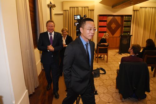 Victoria and Tasmania Consul-General of China Long Zhou (centre) departs a press conference at the Commonwealth Parliamentary Offices in Melbourne.