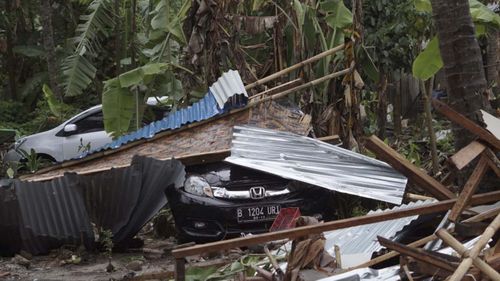 Cars are covered by debris at an area ravaged by a tsunami, in Carita, Indonesia.