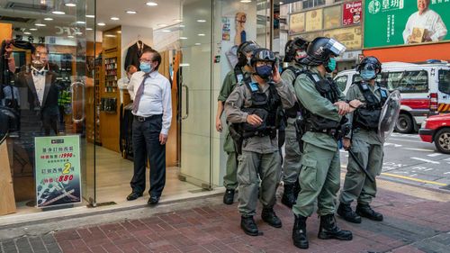 Riot police stand guard outside of a shop during a protest against the national security law.