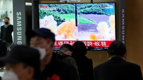 People watch a TV showing a file image of North Korea's missile launch