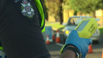 A Victoria Police officer prepares to deliver a roadside alcohol breath test. (9NEWS)