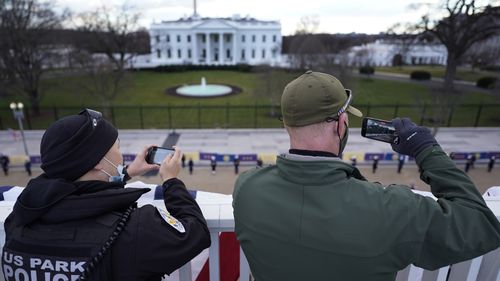 Police take photos as a ceremonial guard passes the White House during a rehearsal for President-elect Joe Biden's inauguration ceremony.